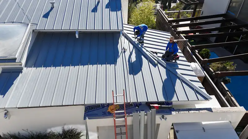 Two Eclipse crew members seaming light gray standing seam panels on a Los Angeles hillside home
