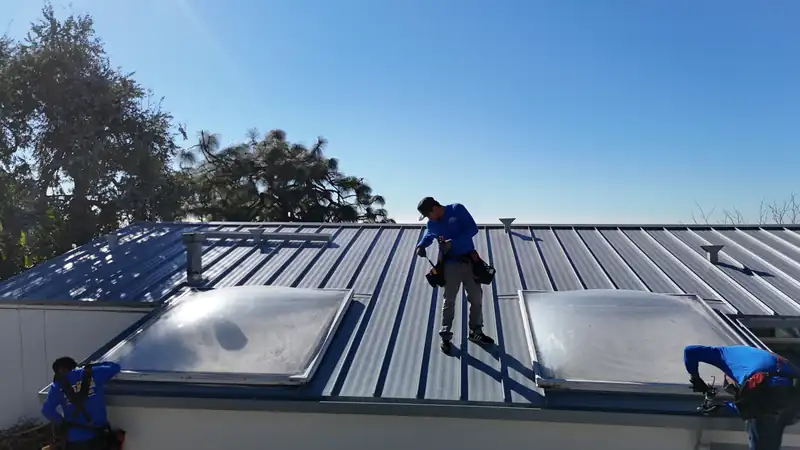 Eclipse crew member walking a light gray standing seam roof between two dome skylights