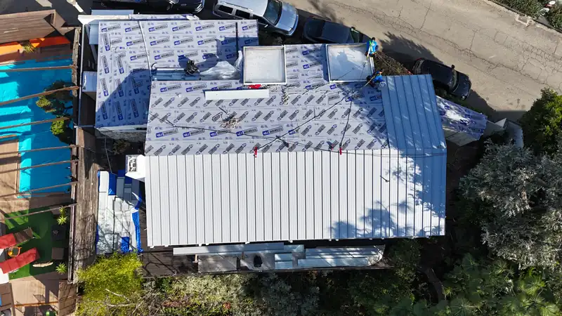 Top-down view of high-temperature underlayment on the deck, with the first standing seam panels going on